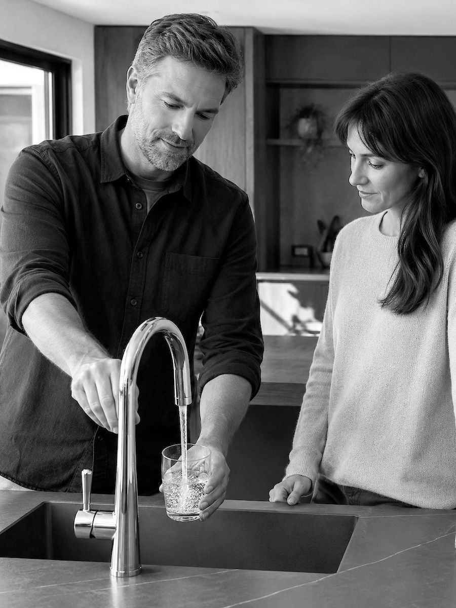 Beratungssituation in der Küche: Ein Glas wird am Wasserhahn gefüllt